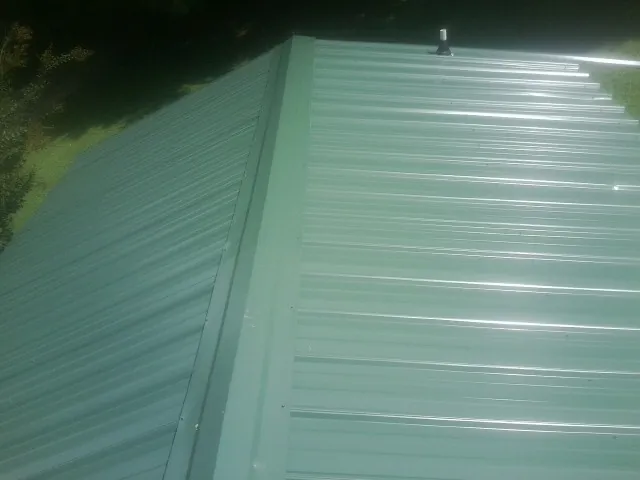 New green metal panels meeting at the ridge of a roof — Flat Roof Repair work by our crew in Ashford