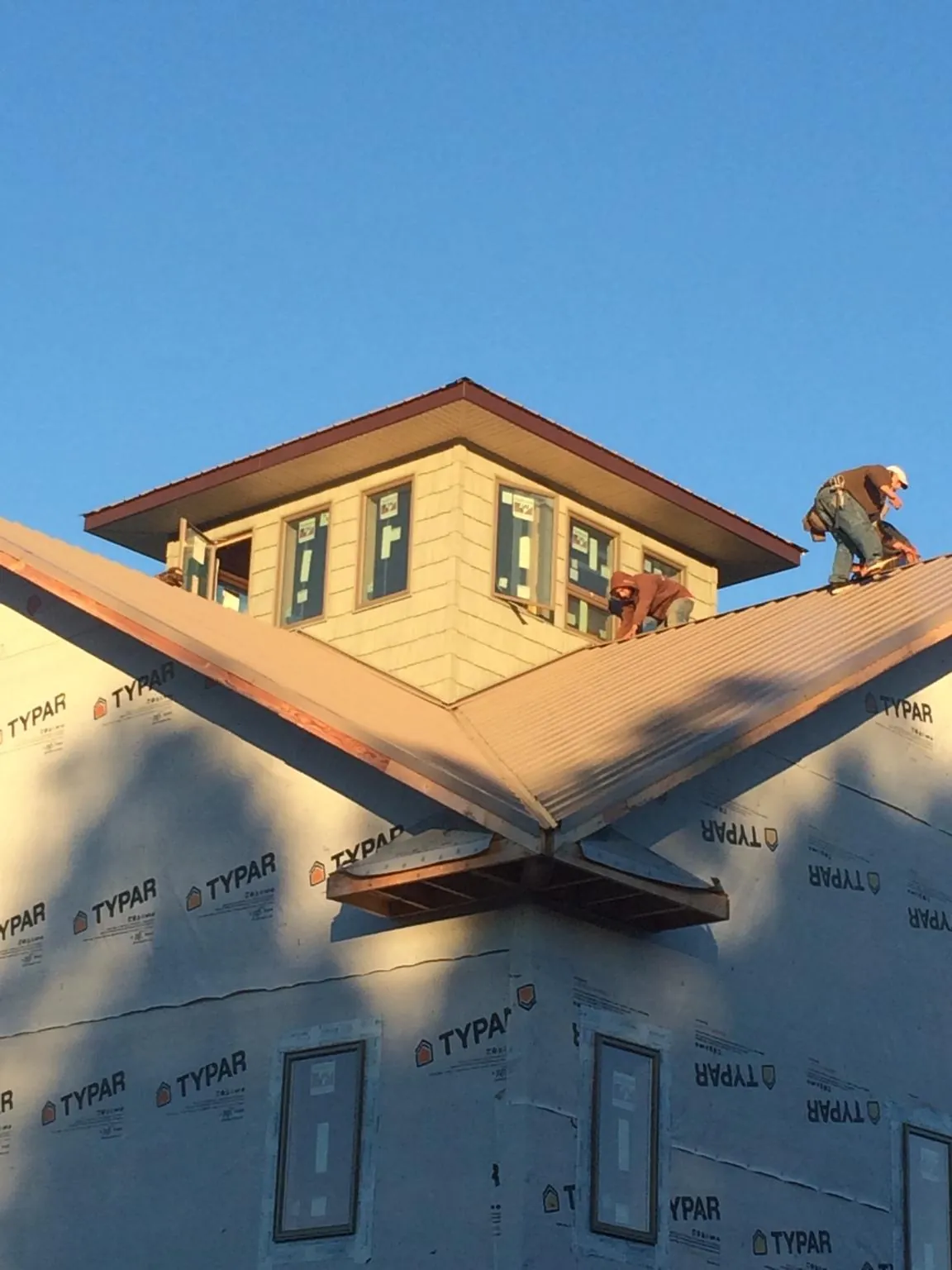 Roofers working around a rooftop cupola on a new metal roof at sunset — Roof Waterproofing in Ashford by Roofing Brothers